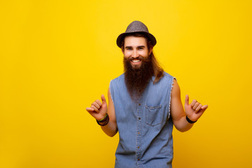 Happy man with long beard isolated on yellow background. Young man standing and gesturing, making...
