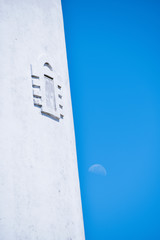 Closed window of a lighthouse overlooking the waning moon.