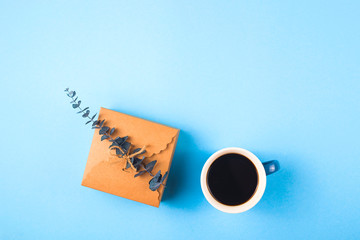 Mom love you written on a decorative panel next to a cup of coffee and eucalyptus on a blue background.