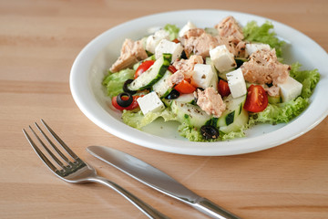 Chicken salad with cherry tomatoes, black olives, cucumber, lettuce. Cesar salad. Concept of a tasty and healthy meal Bright wooden background.