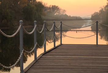 Fototapeta premium Pier by the river during sunset. Chain fence