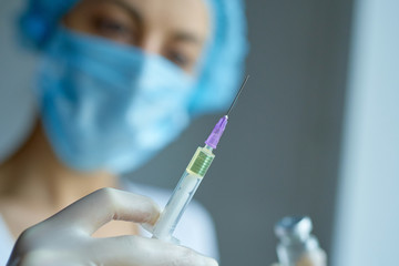 Close-up female doctor holding syringe and vaccine.