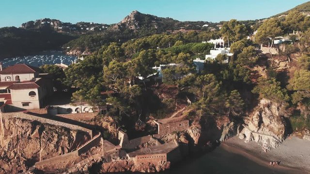 Aerial view of a coastline with a mansion and yachts in the background