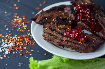 fresh grilled steaks, wild meat with spices on a black background, the concept of food with no GMOs