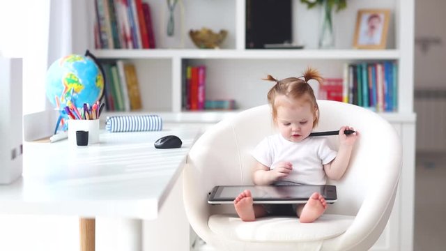 cute little baby girl watching educational video on graphic tablet at home