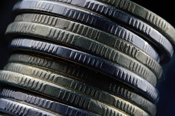 A stack of coins falls on a dark background. Macro.