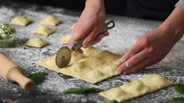 Woman making tasty ravioli on table, closeup
