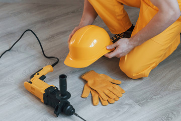 Handyman in yellow uniform with drill standing indoors. House renovation conception