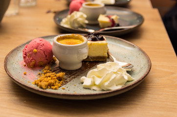 plate with dessert delicacies such as cheesecake with blueberries, raspberry ice cream, creme brulee and whipped cream