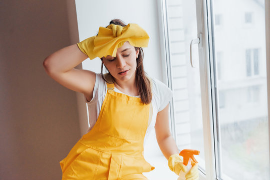Tired housewife in yellow uniform takes a break indoors. House renovation conception - Powered by Adobe