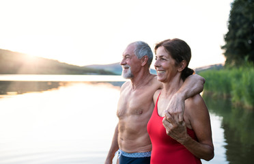 Fototapeta na wymiar Senior couple in swimsuit standing by lake outdoors before swimming.