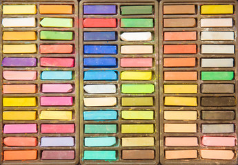 Obraz premium Set of multicolored pastel aquarelle crayons in open wooden artist box, top view