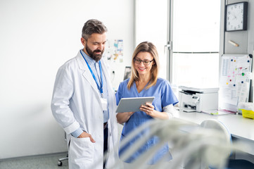 A dentist with dental assistant in modern dental surgery, working.
