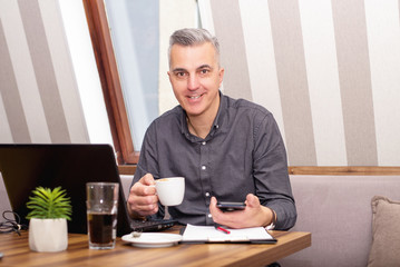 Fototapeta na wymiar Businessman using laptop at phone in the cafe