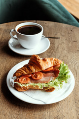 Breakfast in cafe. Croissant with cup of black coffee.