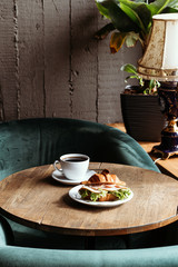 Breakfast in cafe. Croissant with cup of black coffee.