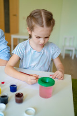 small girl drawing with brush and paints 