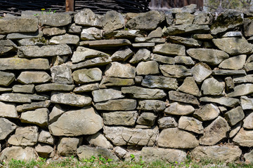 Minimalist monochrome textured natural background of many grey stones in a wall  in sunny spring garden