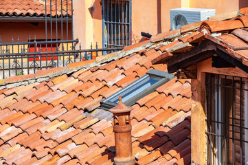 Chimney pipe and old ceramic shingles tile on the roof.