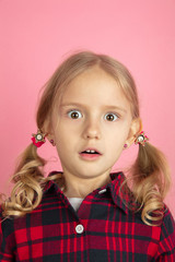 Shocked. Caucasian little girl's close up portrait on pink studio background. Beautiful female...