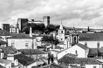 Old town skyline of Obidos, Portugal with house roof tops, church towers and the wall of the medieval castle located in the civil parish of Santa Maria, São Pedro e Sobral da Lagoa, Oeste region.