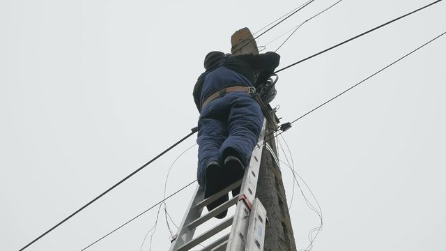 Electricity work, man repairs electric pole wearing all the safety equipment