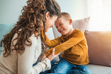 Mother and son playing in a living room. Spending quality time togather. Mother and son laughing. Exited mom and son are entertaining in living room. Parents are playing with children at home concept