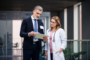 Pharmaceutical sales representative with tablet talking to doctor.