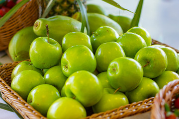 Green apples in a wicker basket outdoors. Fruit. Green fruits.