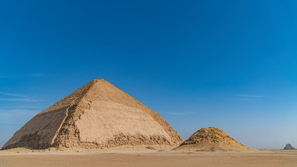 The Bent Pyramid is an ancient Egyptian pyramid located at the royal necropolis of Dahshur, approximately 40 kilometres south of Cairo, built under the Old Kingdom Pharaoh Sneferu. Egypt