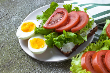 Fototapeta na wymiar Eggs with sandwich with vegetables. Hard boiled eggs and sandwich with cream cheese, tomatoes and lettuce. Healthy food / lunch/ breakfast