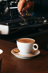Barman sprinkles spices on cocoa. Cooking cocoa in cafe.