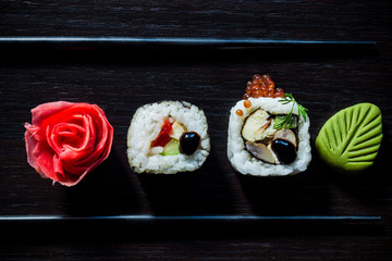 Sushi rolls with caviar, ginger, wassabi and chopsticks top view on black tableboard. Japanese food concept. Still life close up food photo