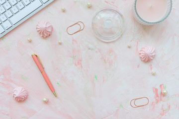 Keyboard, pen, candle, paper clips and meringues on a desk workspace, pink backround. Flat lay, top view, social media hero header template, lifestyle concept.