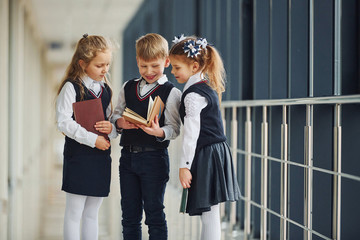 School kids in uniform together with books in corridor. Conception of education