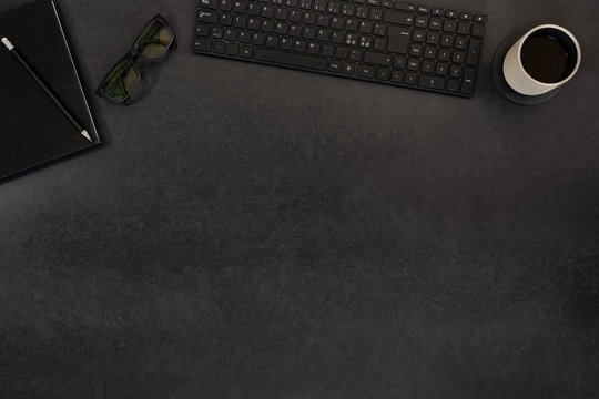 Top view of black concrete office desk with computer and supplies