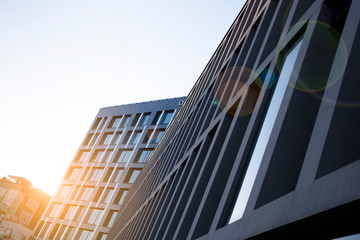 Office building glass facades on a bright sunny day with sunbeams in the blue sky. Abstract view of a skyscraper with sunlight