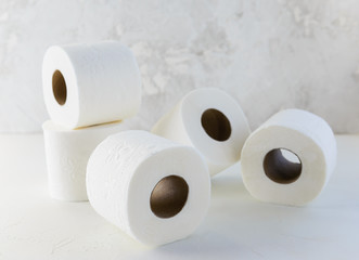 Rolls of white toilet paper on a white table.