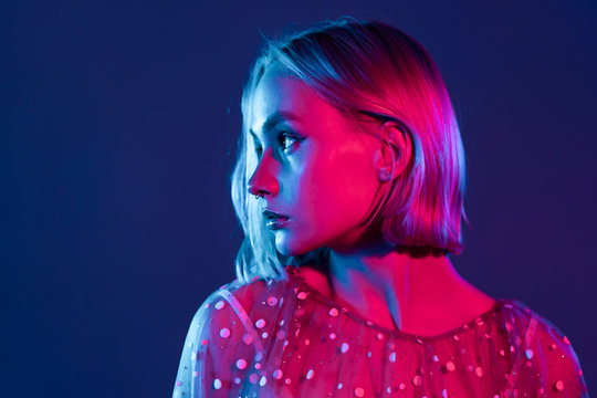 Mysterious hipster teenager. Portrait of millennial pretty girl with short hairstyle with neon light. Dyed blue and pink hair.