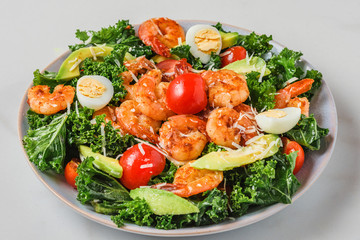 Plate with healthy diet fresh salad made of shrimps, kale, avocado, tomatoes, eggs and cheese for lunch