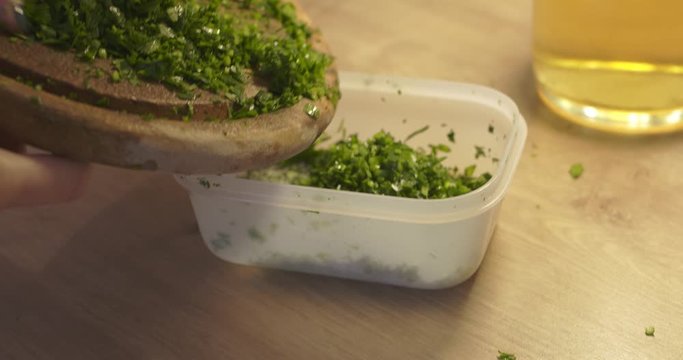 Woman putting chopped parsley in plastic container. Chopped healthy parsley