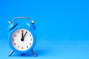 Alarm clock on a blue background, on the right is an empty place