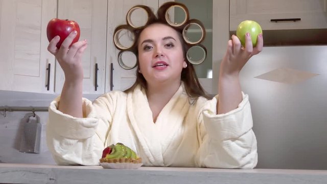 Plus-size girl with curlers on her head dressed in a bathrobe is recording a video blog