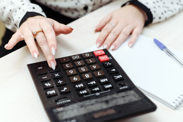 A woman considers on a calculator costs, revenues, expenses. Distribution of the family budget. Businesswomen is engaged in accounting
