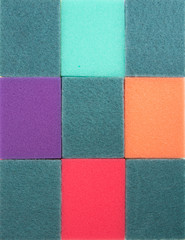 Fototapeta premium Dish washing sponges are laid out in a strict order. Rectangular colored segments made of sponges for washing dishes. Background.