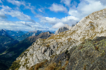 A close up shot of a massive mountain range in Austrian Alps. The rocky mountain looks inaccessible. High Alpine mountaineering. Sun rays coming from above the peaks.