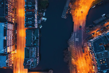 Amsterdam canal, old dancing houses, river Amstel and illuminated streets, aerial top view at night, drone photo.