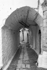 Antigua calle medieval italiana con arco en blanco y negro - obrazy, fototapety, plakaty