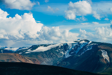 Atmospheric alpine landscape with giant mountains and glaciers. Huge glacial mountains above highland valley. Beautiful view to snowy peak under blue cloudy sky. Wonderful scenery on high altitude.