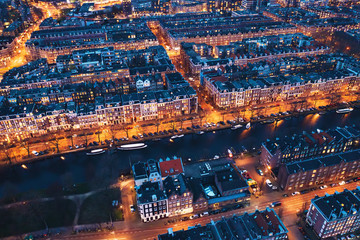 Amsterdam Netherlands aerial view at night. Old dancing houses, river Amstel, canals with bridges, old european city landscape from above.